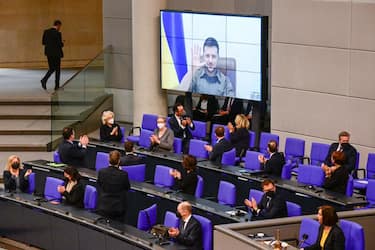 Members of the German government, among them German Chancellor Olaf Scholz (bottom C) applaud as Ukrainian President Volodymyr Zelensky appears on a screen to address via videolink the German lower house of parliament Bundestag, on March 17, 2022 in Berlin. (Photo by Tobias SCHWARZ / AFP) (Photo by TOBIAS SCHWARZ/AFP via Getty Images)