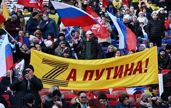 People gather for a concert marking the eighth anniversary of Russia's annexation of Crimea at the Luzhniki stadium in Moscow on March 18, 2022. - The banner bearing the letter "Z" in the colours of the ribbon of Saint George, which has become a symbol of support for Russian military action in Ukraine, reads "For Putin!" (Photo by Pavel BEDNYAKOV / POOL / AFP) (Photo by PAVEL BEDNYAKOV/POOL/AFP via Getty Images)
