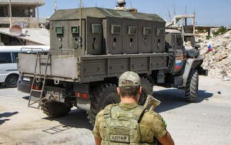 A Russian soldier stands near a Russian military police vehicle in the Syrian rebel-held Daraa al-Balad district of the southern city of Daraa on September 6, 2021 as Russian forces enforce a ceasefire between government forces and local committees as part of reconciliation efforts after several months of siege by government forces. - A Russian-brokered ceasefire came into force on September 1 in Daraa province, the cradle of Syria's uprising where government forces have been battling holdout rebels. The southern province of Daraa, held for years by opposition forces, was returned to government control in 2018 under a previous Moscow-backed ceasefire that had allowed rebels to stay in some areas. (Photo by Sam HARIRI / AFP) (Photo by SAM HARIRI/AFP via Getty Images)