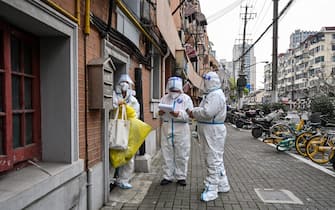 TOPSHOT - Health workers wearing protective gear as a measure against the Covid-19 coronavirus work along a street in Jing'an district in Shanghai on March 26, 2022. (Photo by Hector RETAMAL / AFP) (Photo by HECTOR RETAMAL/AFP via Getty Images)