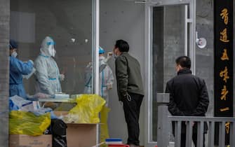 BEIJING, CHINA - MARCH 25: A health worker wears a protective suit as she performs a nucleic acid test to detect COVID-19 on a local resident at a pop-up testing site in the street on March 25, 2022 in Beijing, China. China has stepped up efforts to control a recent surge in coronavirus cases across the country, locking down the entire province of Jilin and the city of Shenyang and putting others like Shenzhen and Shanghai under restrictions. Local authorities across the country are mass testing as China tries to maintain its zero COVID policy. (Photo by Kevin Frayer/Getty Images)