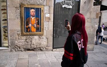 A woman takes a photo of the portrait of Vladimir Putin behind the bars. Vladimir Putin behind bars is represented in the new public graphic collage in Plaza de Sant Jaume by Barcelona-based Italian artist TvBoy. (Photo by Paco Freire / SOPA Images/Sipa USA)