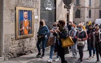 People look on while walking past a portrait of Vladimir Putin behind the bars.  Vladimir Putin behind bars is represented in the new public graphic collage in Plaza de Sant Jaume by Barcelona-based Italian artist TvBoy.  (Photo by Paco Freire / SOPA Images / Sipa USA)