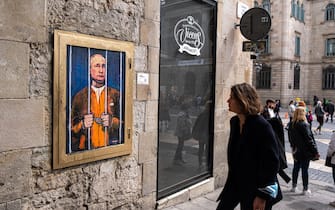 A  woman looks on while walking past a portrait of Vladimir Putin behind the bars. Vladimir Putin behind bars is represented in the new public graphic collage in Plaza de Sant Jaume by Barcelona-based Italian artist TvBoy. (Photo by Paco Freire / SOPA Images/Sipa USA)