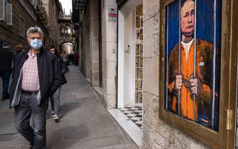 A man walks past a portrait of Vladimir Putin behind the bars.  Vladimir Putin behind bars is represented in the new public graphic collage in Plaza de Sant Jaume by Barcelona-based Italian artist TvBoy.  (Photo by Paco Freire / SOPA Images / Sipa USA)