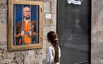 A woman looks at a portrait of Vladimir Putin behind the bars. Vladimir Putin behind bars is represented in the new public graphic collage in Plaza de Sant Jaume by Barcelona-based Italian artist TvBoy. (Photo by Paco Freire / SOPA Images/Sipa USA)