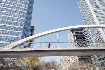 epa09863090 A man crosses a bridge in the central business district of Beijing, China, 01 April 2022. China's use of lockdowns to contain the coronavirus and COVID-19 pandemic around the country will take a toll on the economy, analysts stated. The country's target growth rate of 5.5 percent could lose ten percentage points on a quarterly basis if it sticks to it's zero-COVID-19 strategy, according to a statement from Everbright Securities.  EPA/MARK R. CRISTINO
