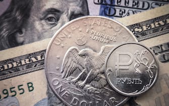 A Russian ruble coin is pictured with US dollar bills and a one dollar coin in Moscow, on March 15, 2022. - Russia has suspended the sale of foreign currencies until September 9, the central bank said in a statement, amid unprecedented economic sanctions on the country following its offensive in Ukraine.  (Photo by AFP) (Photo by - / AFP via Getty Images)