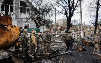 Ukainian President Volodymyr Zelensky (3rdL) stands in the town of Bucha, northwest of the Ukrainian capital Kyiv, on April 4, 2022. - Ukraine's President Volodymyr Zelensky said on April 3, 2022 the Russian leadership was responsible for civilian killings in Bucha, outside Kyiv, where bodies were found lying in the street after the town was retaken by the Ukrainian army. (Photo by RONALDO SCHEMIDT / AFP) (Photo by RONALDO SCHEMIDT/AFP via Getty Images)