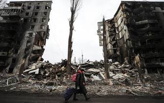 BORODIANKA, UKRAINE - APRIL 05: An Ukrainian walks with a suitcase along the ruins of damaged buildings as the city of Borodianka was the scene of heavy clashes for weeks while the Russian military were located until about four days ago in Borodianka, Ukraine on March 05 , 2022. The Ukrainian forces regained the control of the town.  (Photo by Metin Aktas / Anadolu Agency via Getty Images)