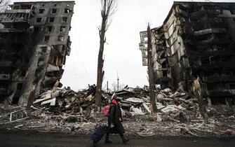 BORODIANKA, UKRAINE - APRIL 05: An Ukrainian walks with a suitcase along the ruins of damaged buildings as the city of Borodianka was the scene of heavy clashes for weeks while the Russian military were located until about four days ago in Borodianka, Ukraine on March 05, 2022. The Ukrainian forces regained the control of the town. (Photo by Metin Aktas/Anadolu Agency via Getty Images)