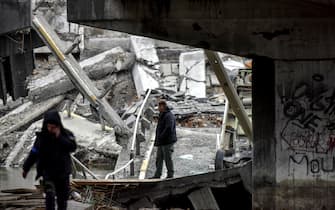 epa09873513 People stand among the rubble of the damaged bridge outside the recaptured city of Irpin, Ukraine, 06 April 2022. Ukrainian forces have recently recaptured from the Russian army some cities and villages in the outskirts of Kyiv.  EPA/OLEG PETRASYUK