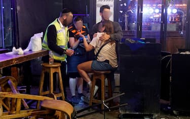 First responders tend to a woman in the aftermath of a shooting attack at a cafe in Dizengoff Street in the centre of Israel's Mediterranean coastal city of Tel Aviv on April 7, 2022. - At least five people were wounded, three severely, during an attack in Tel Aviv on April 7. Eli Bin, head of the Magen David Adom emergency responders, told public TV broadcaster Kan that one of the wounded was "in a critical state," after the latest incident in a surge of violence occurring in Israel and the West Bank. (Photo by JACK GUEZ / AFP) (Photo by JACK GUEZ/AFP via Getty Images)