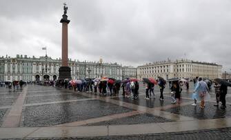 epa07725194 Tourists stand in line at the State Hermitage Museum, during a rainy day in central Petersburg, Russia, 18 July 2019. The daily temperature decrease to 18 degrees Celsius in the cultural capital of Russia.  EPA / ANATOLY MALTSEV