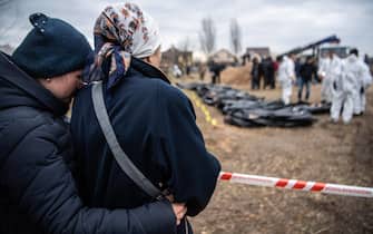 Women watch and embrace each other as bodies are exhumed from a mass grave and inspected by the authorities for possible war crimes in Bucha, a town near Kyiv that was recently liberated from Russian occupation.