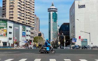 SHANGHAI, CHINA - APRIL 9, 2022 - A food delivery rider passes an empty intersection in Pudong, Shanghai, China, On April 9, 2022. Shanghai is under lockdown. (Photo credit should read Costfoto/Future Publishing via Getty Images)