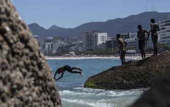 epa09834706 People enjoy the water on Arpoador beach in Rio de Janeiro, Brazil, 18 March 2022. This Friday is the penultimate day of summer in Brazil with high temperatures close to 40 degrees in the city of Rio.  EPA/Antonio Lacerda