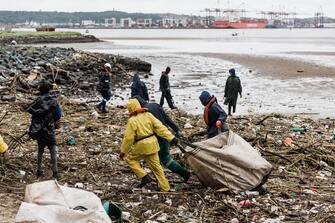 TOPSHOT - Volunteers clean up massive deris at the Durban harbour following heavy rains, mudslides and rain and winds in Durban, on April 16, 2022 as the death toll from the disaster that struck the coastal city of Durban surged passed 350 wreaking havoc in the surrounding region destryoing homes and infrastructer. The harbour serves as a bulwark for the economy of the city of Durban - South Africa's flood-ravaged east was hit by more rain Saturday after the deadliest storm to strike the country in living memory killed nearly 400 people and left tens of thousands homeless. (Photo by RAJESH JANTILAL / AFP) (Photo by RAJESH JANTILAL/AFP via Getty Images)