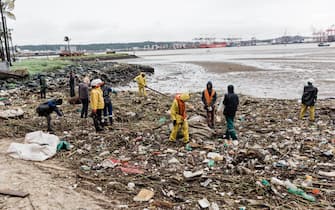 Volunteers clean up massive deris at the Durban harbor following heavy rains, mudslides and rain and winds in Durban, on April 16, 2022 as the death toll from the disaster that struck the coastal city of Durban surged passed 350 wreaking havoc in the surrounding region destryoing homes and infrastructer.  The harbor serves as a bulwark for the economy of the city of Durban - South Africa's flood-ravaged east was hit by more rain Saturday after the deadliest storm to strike the country in living memory killed nearly 400 people and left tens of thousands homeless.  (Photo by RAJESH JANTILAL / AFP) (Photo by RAJESH JANTILAL / AFP via Getty Images)