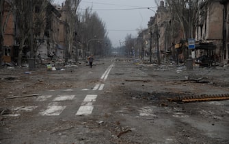MARIUPOL, UKRAINE - 2022/04/09: A woman walks along in a destroyed Mariupol street. The battle between Russian / Pro Russian forces and the defending Ukrainian forces led by the Azov battalion continues in the port city of Mariupol. (Photo by Maximilian Clarke/SOPA Images/LightRocket via Getty Images)