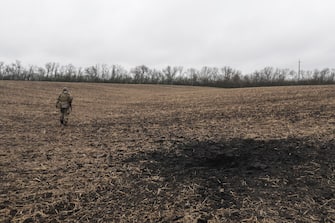 epa09899649 A Ukrainian serviceman walks on a field with a shelling hole in the Kharkiv area, Ukraine, 20 April 2022. The city of Kharkiv, Ukraine's second-largest city, has witnessed repeated airstrikes from Russian forces including satellite cities. Russian troops entered Ukraine on 24 February resulting in fighting and destruction in the country and triggering a series of severe economic sanctions on Russia by Western countries.  EPA/STR