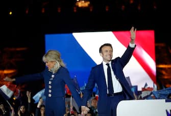 epa09907434 French President Emmanuel Macron and his wife Brigitte Macron celebrate on the stage after winning the second round of the French presidential elections at the Champs-de-Mars after Emmanuel Macron won the second round of the French presidential elections in Paris, France, 24 April 2022. Emmanuel Macron defeated Marine Le Pen in the final round of France's presidential election, with exit polls indicating that Macron is leading with approximately 58 percent of the vote.  EPA/YOAN VALAT