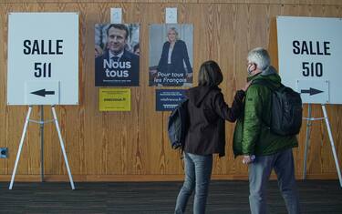 MONTREAL, QUEBEC - APRIL 23:  French citizen walk by posters of candidates Emmanuel Macron and Marine Le Pen as they go to vote in the second round of France's presidential election at the Palais des Congres on April 23, 2022 in Montreal, Quebec. Emmanuel Macron and Marine Le Pen both qualified on Sunday, April 10 for France's Presidential Election second round to be held on April 24. (Photo by Hong Wu/Getty Images)