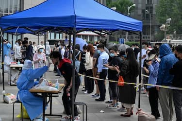 People line up to be tested for Covid-19 coronavirus at a makeshift testing site outside office buildings in Beijing on April 25, 2022. (Photo by Jade GAO / AFP) (Photo by JADE GAO/AFP via Getty Images)