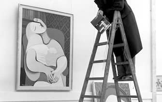 A visitor stands on a ladder to observe the painitng "Le Rêve (The Dream)" from 1932 in the exhibition, which will be shown for two months under the topic "Picasso Retrospective". The exhibition includeds 250 works of the Spanish painter Pablo Picasso, who celebrates his 74th birthday on the opening day on 25 October 1955. | usage worldwide (Photo by Georg Goebel/picture alliance via Getty Images)