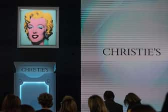 epa09936986 Bidders take their seats in the audience before The Evening Sale of works from The Collection of Thomas and Doris Amman at Christie's Auction House in New York, New York, USA, 09 May 2022.  'Shot Sage Blue Marilyn' by Andy Warhol, is displayed behind the podium, which is the highlight of the night.  EPA/SARAH YENESEL