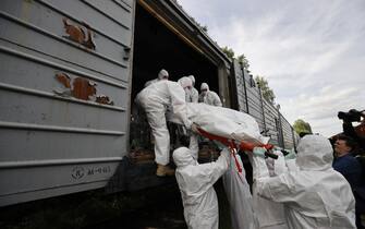 KYIV, UKRAINE - MAY 13: Officials wearing protective suits store bodies of Russian soldiers who lost their lives in conflicts in various cities of Ukraine, at the refrigerator railway wagons in Kyiv, Ukraine on May 13, 2022. (Photo by Dogukan Keskinkilic/Anadolu Agency via Getty Images)