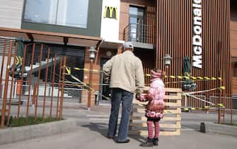 A man and a little girl look at a closed McDonald's in the Crimean capital Simferopol on April 4, 2014. US fast food giant McDonald's said today it was temporarily shutting its three stores in Crimea following the Ukrainian peninsula's annexation by Russia.  AFP PHOTO / YURIY LASHOV (Photo credit should read YURIY LASHOV / AFP via Getty Images)