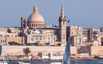 White yacht and boats in harbor of Valletta, Our Lady of Mount Carmel church and St. Paul's Anglican Pro-Cathedral on the background, Valletta, Malta