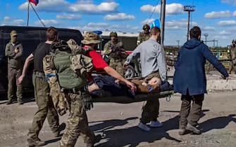 epa09952380 A handout still image taken from a handout video made available by the Russian Defence Ministry's press service shows Ukrainian servicemen carry a wounded comrade as they are being evacuated from the besieged Azovstal steel plant in Mariupol, Ukraine, 17 May 2022. A total of 265 Ukrainian militants, including 51 seriously wounded, have laid down arms and surrendered to Russian forces, the Russian Ministry of Defence said on 17 May 2022. Those in need of medical assistance were sent for treatment to a hospital in Novoazovsk, the ministry states further. Russian President Putin on 21 April 2022 ordered his Defence Minister to not storm but to blockade the plant where a number of Ukrainian fighters were holding out. On 24 February, Russian troops invaded Ukrainian territory starting a conflict that has provoked destruction and a humanitarian crisis. According to the UNHCR, more than six million refugees have fled Ukraine, and a further 7.7 million people have been displaced internally within Ukraine since.  EPA/RUSSIAN DEFENCE MINISTRY PRESS SERVICE HANDOUT  BEST QUALITY AVAILABLE HANDOUT EDITORIAL USE ONLY/NO SALES