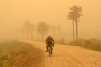 A man rides his bicycle during a sandstorm in Iraq's southern city of Basra on May 16, 2022. - Another sandstorm that descended on climate-stressed Iraq sent at least 4,000 people to hospital with breathing problems and led to the closure of airports, schools and public offices across the country. (Photo by Hussein Faleh / AFP) (Photo by HUSSEIN FALEH/AFP via Getty Images)