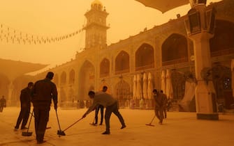 TOPSHOT - Volunteers clean up at the Imam Ali shrine during a sandstorm in Iraq's holy city of Najaf on May 16, 2022. - Another sandstorm that descended on Iraq sent at least 2,000 people to hospital with breathing problems and led to the closure of airports, schools and public offices across the country. (Photo by Qassem al-KAABI / AFP) (Photo by QASSEM AL-KAABI/AFP via Getty Images)