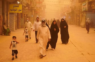 People walk down al-Rasoul street leading to the Imam Ali shrine during a sandstorm in Iraq's holy city of Najaf on May 16, 2022. - Another sandstorm that descended on Iraq sent at least 2,000 people to hospital with breathing problems and led to the closure of airports, schools and public offices across the country. (Photo by Qassem al-KAABI / AFP) (Photo by QASSEM AL-KAABI/AFP via Getty Images)