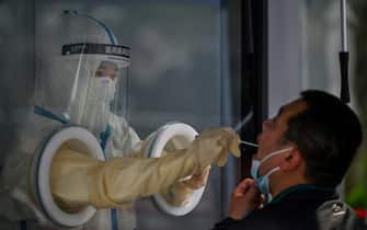 A health worker takes a swab sample from a man during a Covid-19 coronavirus lockdown in the Jing'an district in Shanghai on May 27, 2022. (Photo by Hector RETAMAL / AFP) (Photo by HECTOR RETAMAL/AFP via Getty Images)