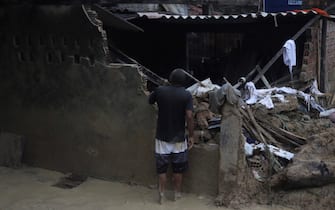 A man looks inside a damaged house after a landslide in the community Jardim Montes Verdes, Ibura neighbourhood, in Recife, Pernambuco State, Brazil, on May 31, 2022. - The death toll from torrential rains that triggered floods and landslides in northeastern Brazil has risen to 100, officials said Tuesday, as emergency workers searched for more victims. (Photo by SERGIO MARANHAO / AFP) (Photo by SERGIO MARANHAO/AFP via Getty Images)