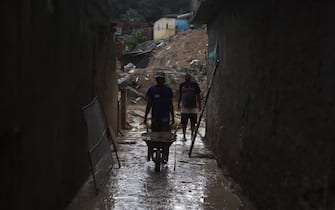 Men remove mud from a damaged house after a landslide in the community Jardim Montes Verdes, Ibura neighbourhood, in Recife, Pernambuco State, Brazil, on May 31, 2022. - The death toll from torrential rains that triggered floods and landslides in northeastern Brazil has risen to 100, officials said Tuesday, as emergency workers searched for more victims. (Photo by SERGIO MARANHAO / AFP) (Photo by SERGIO MARANHAO/AFP via Getty Images)