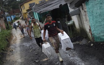 TOPSHOT - Men walk carrying belongings removed from houses affected by heavy rains and a landslide in the community Vila dos Milagres, Barro neighbourhood, in Recife, Pernambuco State, Brazil, on May 31, 2022. - The death toll from torrential rains that triggered floods and landslides in northeastern Brazil has risen to 100, officials said Tuesday, as emergency workers searched for more victims. (Photo by SERGIO MARANHAO / AFP) (Photo by SERGIO MARANHAO/AFP via Getty Images)