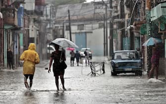 epa09994484 Several people walk along a flooded street in Havana, Cuba, 03 June 2022. The remnant of Hurricane Agatha, which left nine dead and four missing in Mexico, is causing intense and persistent rains this Friday in western Cuba. The island's authorities have already warned about this meteorological phenomenon, which according to the US National Hurricane Center (NHC) continues to strengthen and may become the first tropical storm in the Atlantic this season.  EPA / Ernesto Mastrascusa