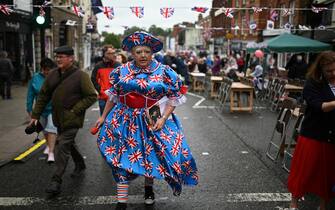 A reveller wearing a dress bearing British national flags arrives to attend a street party in Ashby-de-la-Zouch in central England on June 5, 2022 as part of Queen Elizabeth II's platinum jubilee celebrations. - Millions of people are expected to attend "Big Jubilee Lunch" picnics, as a long weekend of festivities to honour Queen Elizabeth II's historic Platinum Jubilee concludes. (Photo by Oli SCARFF / AFP) (Photo by OLI SCARFF/AFP via Getty Images)