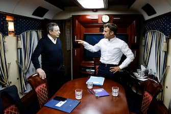 epa10015402 Italian Prime Minister Mario Draghi (L) and French President Emmanuel Macron chat as they travel with German Chancellor Olaf Scholz (not pictured) inside a train carriage from an undisclosed location in Poland to Kyiv, Ukraine, 16 June 2022. The three EU leaders will meet Ukrainian President Volodymyr Zelensky.  EPA/LUDOVIC MARIN / POOL MAXPPP OUT