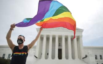 WASHINGTON, DC - JUNE 15: Joseph Fons holding a Pride Flag in front of the U.S. Supreme Court building after the court ruled that LGBTQ people can not be disciplined or fired based on their sexual orientation, Washington, DC, June 15, 2020. With Chief Justice John Roberts and Justice Neil Gorsuch joining the Democratic appointees, the court ruled 6-3 that the Civil Rights Act of 1964 bans bias based on sexual orientation or gender identity. Fons is wearing a Black Lives Matter mask with the words 'I Can't Breathe', as a precaution against Covid-19. (Photo by Chip Somodevilla/Getty Images)