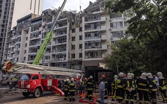 epa10034563 Firefighters and rescuers stand in front of a damaged residential building following Russian airstrikes in the Shevchenkivskiy district of Kyiv (Kiev), Ukraine, 26 June 2022. Multiple airstrikes hit the center of Kyiv in the morning. Russian troops on 24 February entered Ukrainian territory, starting the conflict that has provoked destruction and a humanitarian crisis.  EPA/ROMAN PILIPEY