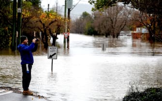 A man takes pictures of the flooded streets due to torrential rain in the Camden suburb of Sydney on July 3, 2022. - Thousands of Australians were ordered to evacuate their homes in Sydney on July 3 as torrential rain battered the country's largest city and floodwaters inundated its outskirts. (Photo by Muhammad FAROOQ / AFP) (Photo by MUHAMMAD FAROOQ/AFP via Getty Images)