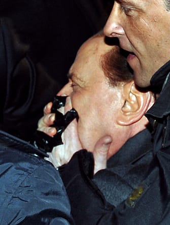 Italian Prime Minister Silvio Berlusconi (L) is help by his security guards after being assaulted in Milan on December 13, 2009 as he was leaving a political meeting.  Italian police have arrested a man who threw a punch at Prime Minister Silvio Berlusconi after a meeting in Milan.  Berlusconi collapsed after being hit and his entourage di lui immediately got him into a car and drove him away.  AFP PHOTO / ANSA / LIVIO ANTICOLI (Photo by LIVIO ANTICOLI / POOL / AFP) (Photo by LIVIO ANTICOLI / POOL / AFP via Getty Images)