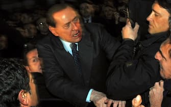 Italian Prime Minister Silvio Berlusconi (C) reacts after being assaulted in Milan on December 13, 2009 as he leaves a political meeting.  Italian police have arrested a man who threw a punch at Prime Minister Silvio Berlusconi after a meeting in Milan.  Berlusconi collapsed after being hit and his entourage di lui immediately got him into a car and drove him away.  AFP PHOTO / ANSA / LIVIO ANTICOLI (Photo by LIVIO ANTICOLI / POOL / AFP) (Photo by LIVIO ANTICOLI / POOL / AFP via Getty Images)