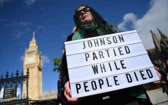 epa09975099 A protester demonstrates against the Downing Street parties, outside parliament in London, Britain, 25 May 2022. British Prime Minister Boris Johnson is under pressure over 'party gate' allegations following new photographs showing him at a drinks party during lockdown.  EPA/ANDY RAIN